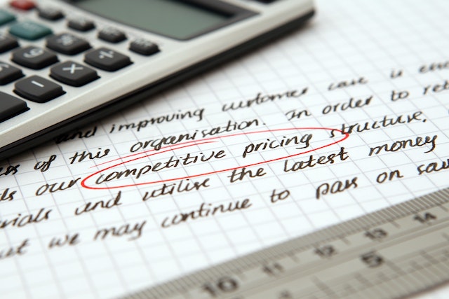calculator on piece of paper with competitive pricing circled in red